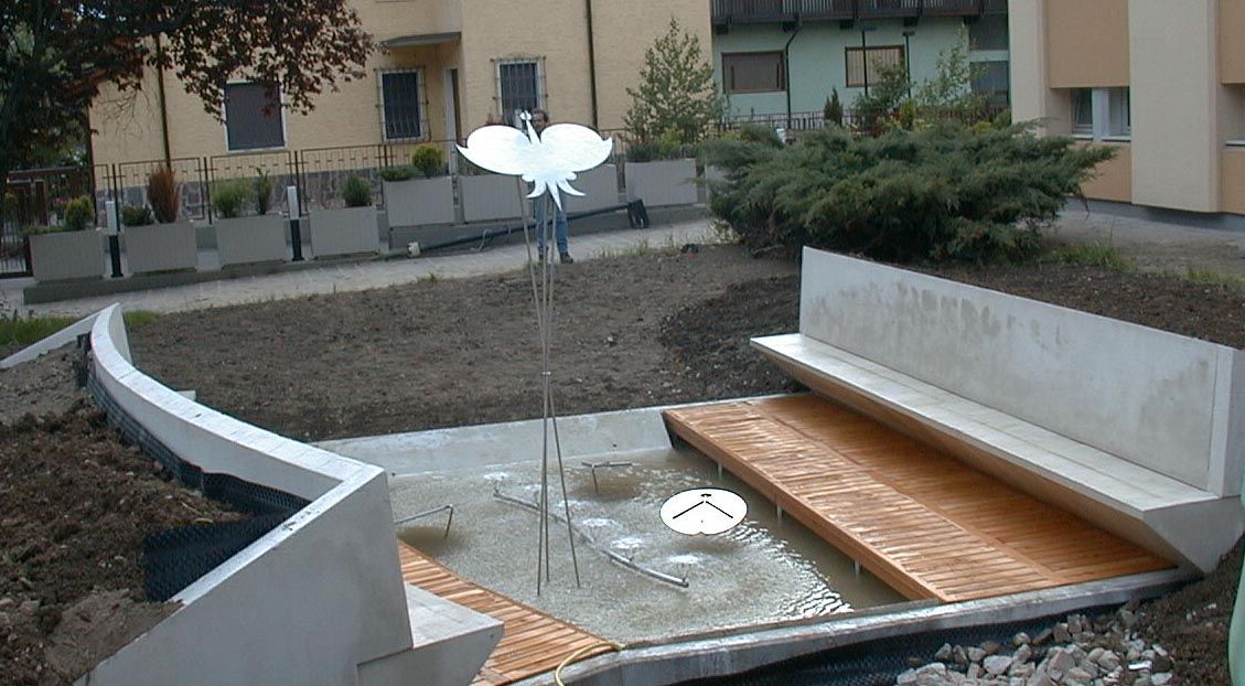 Specchio d'acqua in un giardino con panche in legno e scultura in acciaio