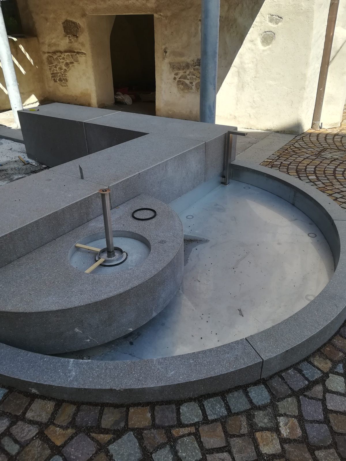 Fontana con vasca circolare in pietra e meccanismo in acciaio, vista dall'alto