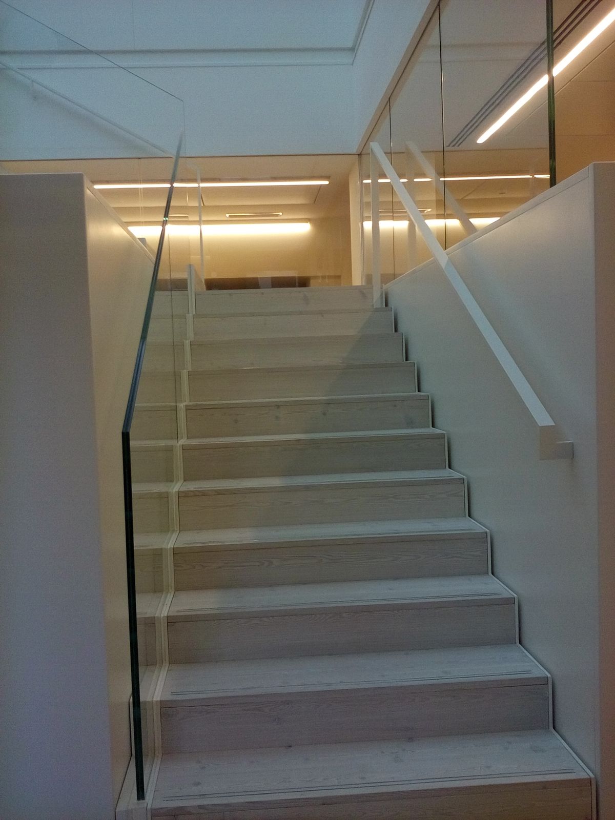 Scala con gradini chiari e parapetto in vetro in un edificio storico ristrutturato