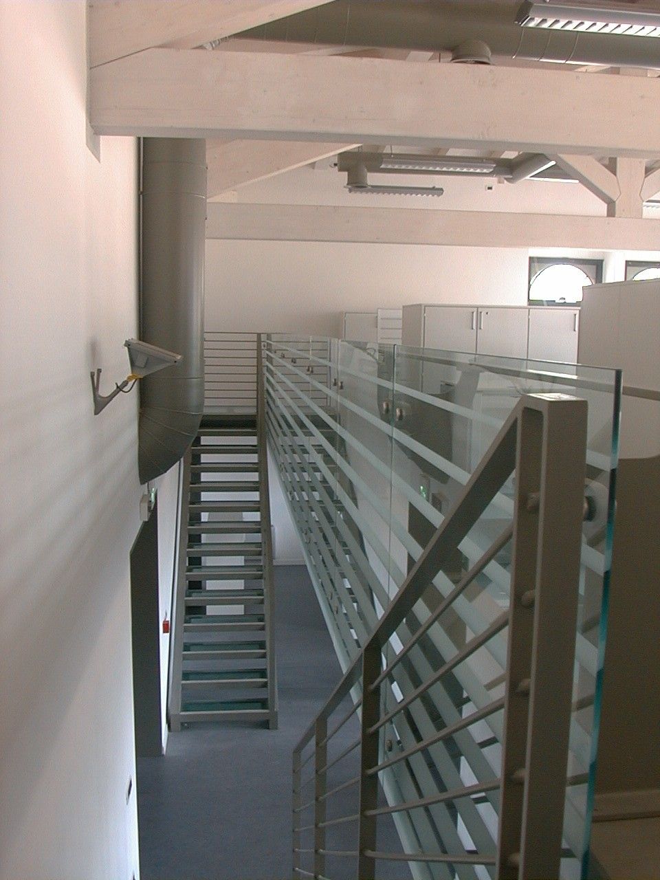 Scala e parapetto in vetro lungo un soppalco, vista verticale