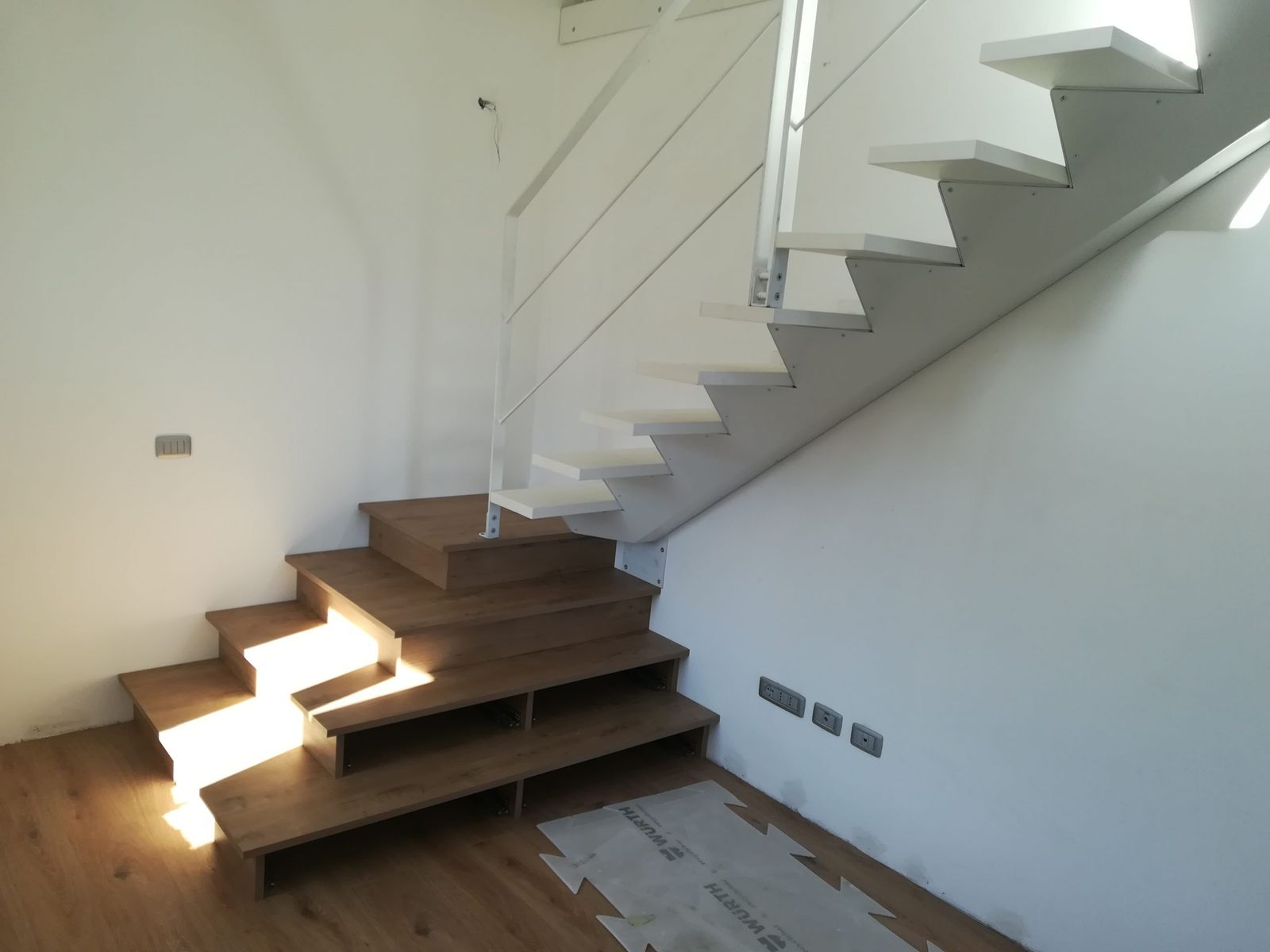 Scala a sbalzo con gradini in legno su parete bianca