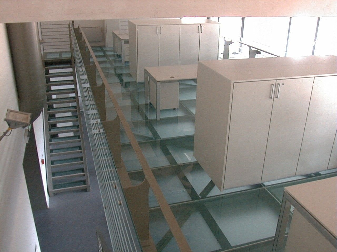 Scala con gradini in grigliato e pavimento in vetro in un ufficio